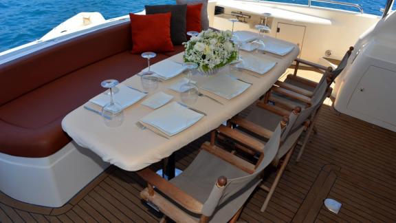 The motor yacht Act features an elegant dining table adorned with flowers and a sea view.